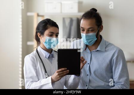 Concentrated diverse doctor and patient using digital tablet. Stock Photo