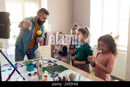 Group of little kids working on project with teacher during creative art and craft class at school. Stock Photo