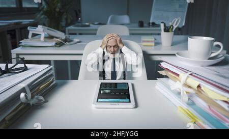 Shocked business executive checking financial reports and statistics on his smartphone, business failure and bankruptcy concept Stock Photo