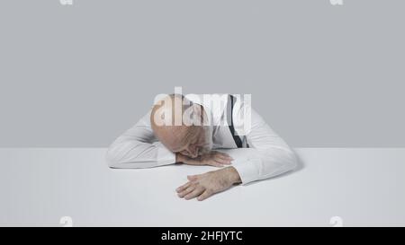 Sad businessman sleeping at desk, he is depressed and tired Stock Photo
