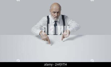 Confident middle aged businessman pointing at blank copy space, information and advertising concept Stock Photo