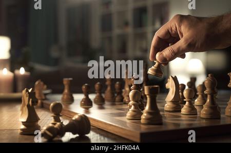 Man holding a chess piece and playing alone at home, hand close up Stock Photo