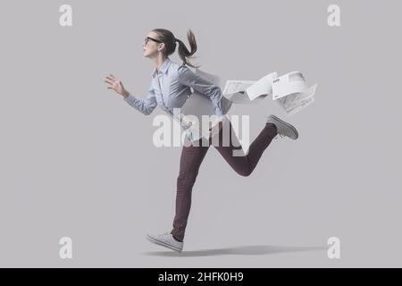 Stressed businesswoman running and losing her paperwork, deadlines concept Stock Photo