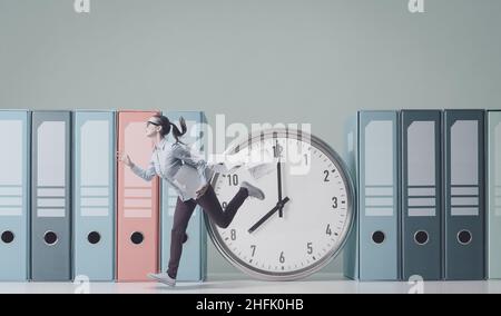 Stressed woman running fast and huge clock: time management and business deadlines concept Stock Photo
