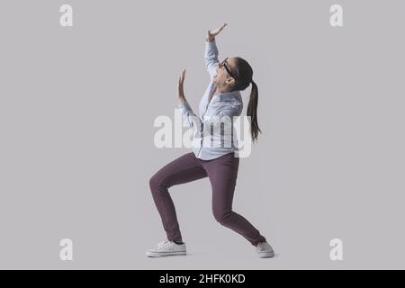 Scared woman protecting herself from a danger, something is falling over her, isolated on gray background Stock Photo