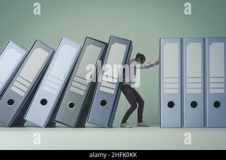 Businesswoman holding and supporting falling ring binders, she is tidying up and organizing the office Stock Photo