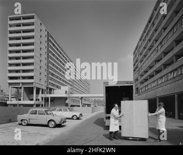 Aylesbury Estate, Walworth, Southwark, London, 01/05/1971. A view of two men delivering a free-standing cupboard to a block of flats on the Aylesbury Estate, built using the 12M Jespersen system. In 1963, John Laing and Son Ltd bought the rights to the Danish industrialised building system for flats known as Jespersen (sometimes referred to as Jesperson). The company built factories in Scotland, Hampshire and Lancashire producing Jespersen prefabricated parts and precast concrete panels, allowing the building of housing to be rationalised, saving time and money. Laing's Southern Region started Stock Photo