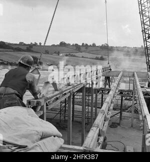 County High School, Gedling Road, Arnold, Gedling, Nottinghamshire, 12/09/1958. Two workers guiding a 'Laingspan' beam, lowered from a crane, into position on the roof of one of the blocks at Arnold County High School, during its construction. Work began on the site in March 1958 and construction was completed for the new school term in September 1959. 'Laingspan' was a flexible modular system of frame construction using precast pre-stressed concrete units. Laing developed the system in conjunction with the Architects and Buildings Branch of the Ministry of Education and consulting engineer AJ Stock Photo