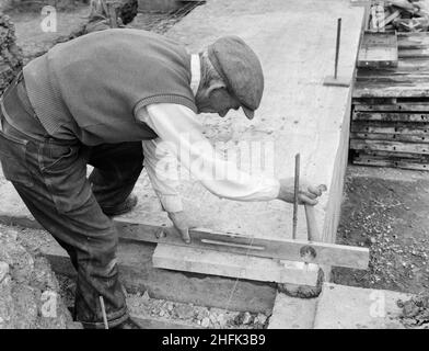 County High School, Gedling Road, Arnold, Gedling, Nottinghamshire, 30/08/1958. A worker using a spirit level to precisely lay a concrete footing slab for a 'Laingspan' wall during the construction of Arnold County High School. Work began on the site in March 1958 and construction was completed for the new school term in September 1959. 'Laingspan' was a flexible modular system of frame construction using precast pre-stressed concrete units. Laing developed the system in conjunction with the Architects and Buildings Branch of the Ministry of Education and consulting engineer AJ Harris. The Arn Stock Photo