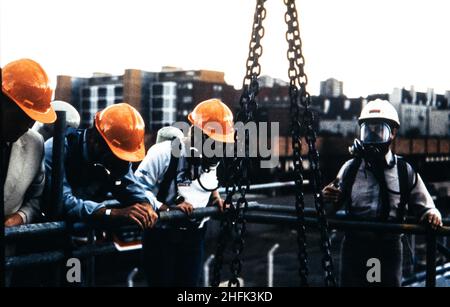 British Library, Euston Road, St Pancras, Camden, London, c June 1984. Four men in hard hats and breathing apparatus during a safety training exercise at the British Library. Everyone on the course had to climb the ladder in the 2m diameter mock-up foundation shaft from a trial depth of 5m wearing breathing apparatus.  This was to replicate the conditions of working at the base of shafts to secure the foot of the steel columns that would support the 5 basement book storage levels.  119 steel columns with brackets to support the basement floor slabs were installed in 20m deep 2m diameter shafts Stock Photo
