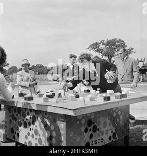 Laing Sports Ground, Rowley Lane, Elstree, Barnet, London, 30/06/1956. People playing the 'hoopla' game during a Laing sports day at Elstree, showing a table with prizes on small blocks and a man collecting the hoops ready for the next round. This sports day was attended by many Laing staff members and their families, with some travelling to Elstree from as far as Swindon, Leicester and Dagenham. The day consisted of various track and field events as well as attractions for children including fairground rides and performers. Handicraft, cookery, flower and photography competitions were also he Stock Photo