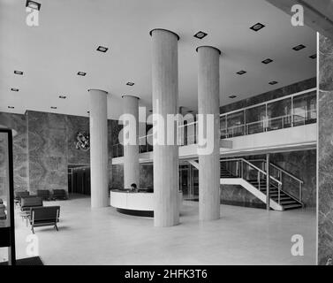 Paternoster Square, City of London, 23/06/1965. The reception area of an office building at the Paternoster development, showing a desk between four large columns. Work on the Paternoster development was carried out in a joint venture by John Laing Construction Limited, Trollope and Colls Limited, and George Wimpey and Company Limited. The scheme involved the redevelopment of a seven acre site on the north side of St Paul&#x2019;s Cathedral. The site had been almost entirely devastated during an incendiary raid in December 1940. The development consisted of a series of office blocks, a shoppin Stock Photo