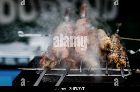 Shashlik or shish kebab prepared on barbecue grill over hot charcoal. Grilled pieces of pork meat on metal skewers. Stock Photo