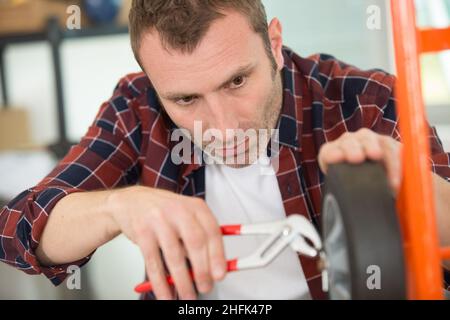 man repairing trolley wheel in workshop Stock Photo