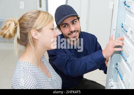electrician inspecting a fusebox with female customer Stock Photo