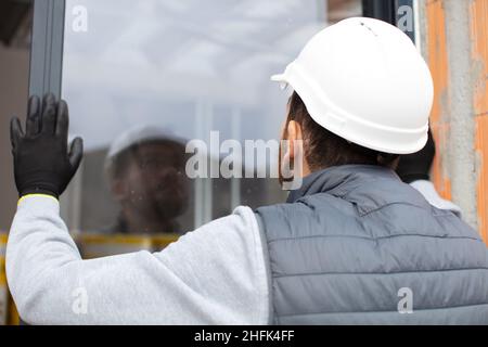 rear view of worker installing upvc window Stock Photo