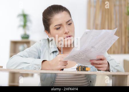 unsure woman assembling kitchen cupboard Stock Photo