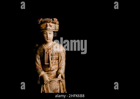 Antique figure of a Japanese geisha  in ivory decorated by hand on a black  blank background. Stock Photo