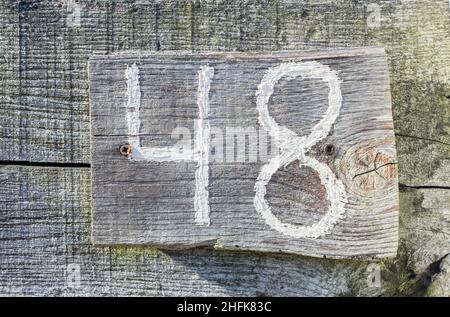 A number 48 painted in white on a wooden board. forty eight Stock Photo