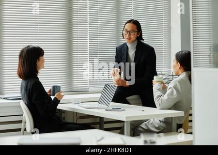 Portrait of smiling Asian businessman chatting with colleagues during coffee break in office Stock Photo