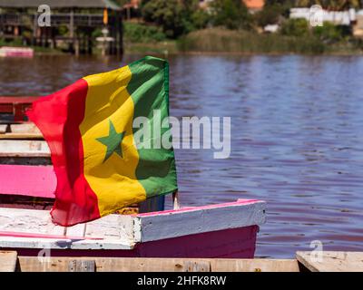 Lac Rose, Senegal - February 2019: Wooden boats with Senegalese flag on the shore of Lake Retba. Africa Stock Photo