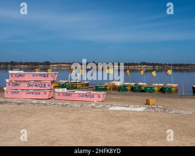 Lac Rose, Senegal - February 2019: Wooden boats with Senegalese flag on the shore of Lake Retba. Africa Stock Photo