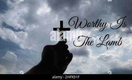 Christianity concept - Worthy is the Lamb with hand holding a Cross. Stock Photo