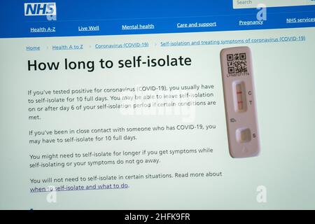 A positive lateral flow test cassette placed next to advice from the NHS website, in London. The UK Health Security Agency have said people in England may be able to leave self-isolation on or after day 6 of your self-isolation period if you have 2 negative tests on day 5 and 6. Picture date: Monday January 17, 2022. Stock Photo