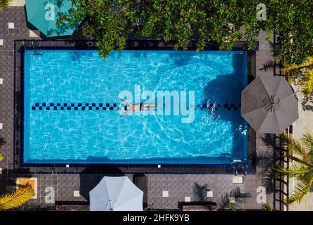 Underwater swimmer man diving in the luxury villa swimming pool. Aerial top shot. Careless summer vacation concept image. Stock Photo