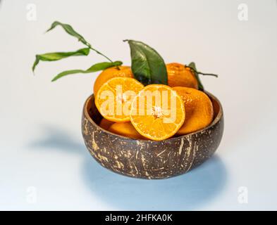 tangerines with leaves in a wooden coconut bowl on a white background Stock Photo