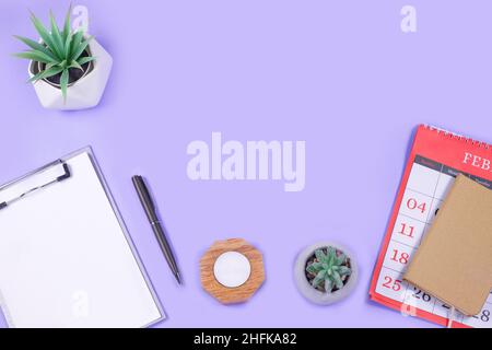 Calendar, Open notebook, pen, with alarm and green flowerpot on purple background. Business, education, working concept. Stock Photo