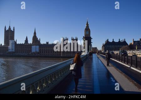 London, UK 13th January 2022. People walk past the Houses of Parliament on Westminster Bridge on a clear, sunny day. Stock Photo