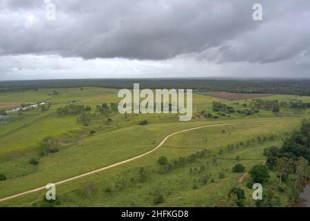 Aerial of dirt road passing through grass paddock on the banks of the Kolan River at Smiths Crossing near Bundaberg Queensland Australia Stock Photo