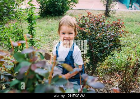 Little girl walks in the garden among beautiful evergreen southern plants Stock Photo
