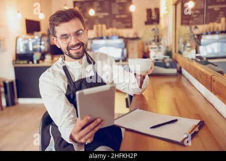 Cheerful male worker using tablet computer in cafe Stock Photo