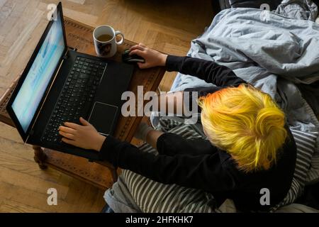 Boy with yellow hair playing game on laptop Stock Photo