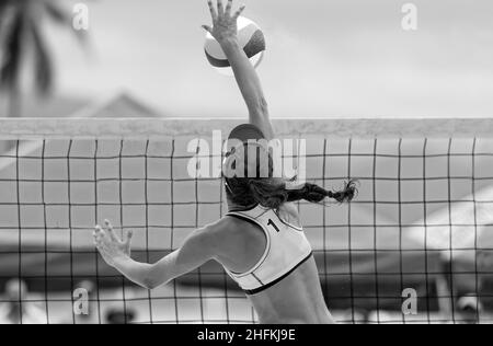 A Female Beach Volleyball Player Is Rising At The Net To Strike The Ball The Ball In Black And White Image Format Stock Photo