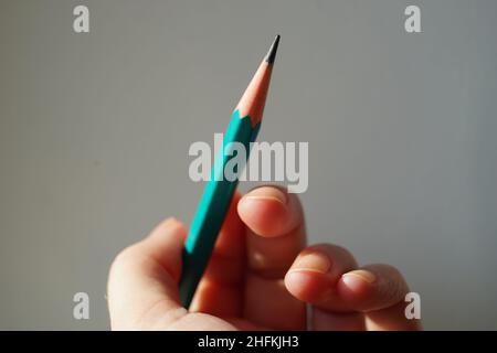Green graphite pencil in human hand with sunlight. Stock Photo
