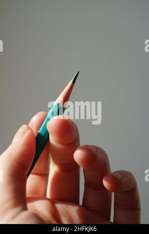 Green graphite pencil in female hand with sunlight. Stock Photo