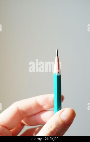 Graphite pencil in human hand. White wall background. Stock Photo