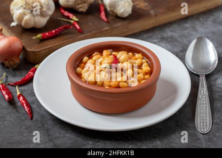Hot turkish bean stew on dark background. Ispir beans cooked in a casserole - Kuru Fasulye Stock Photo