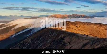 Meadows and Hills in Low Tatra Mountains National Park over clouds, Slovakia landscape in autumn Stock Photo