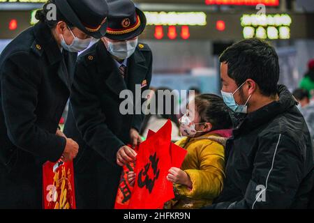 (220117) -- GUIYANG, Jan. 17, 2022 (Xinhua) -- Staff members give New Year gifts to passengers at Guiyang Railway Station in Guiyang, southwest China's Guizhou Province, Jan. 17, 2022. China's 2022 Spring Festival travel season is expected to see 1.18 billion passenger trips, up 35.6 percent year on year, but 20.3 percent lower than that of 2020, the Ministry of Transport has said. The 40-day travel season, also known as chunyun, kicked off Monday and many people will travel to reunite with their families for the Lunar New Year, or the Spring Festival, which falls on Feb. 1 this year. (Xin Stock Photo