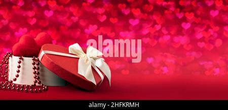 happy valentine's day gifts. red heart-shaped box, beads and hearts inside and on the background. panoramic copy space empty layout. Stock Photo