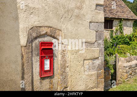 ER Elizabeth II red post box inserted in an old stone window moulding in the wall of an old farmhouse in the Cotswold hamlet of Hawkesbury, Gloucester Stock Photo