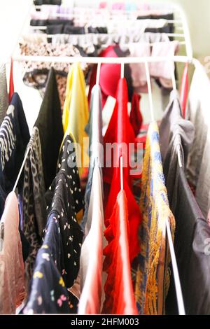 Colorful different dress and laundry hanging on a drying rack. Stock Photo