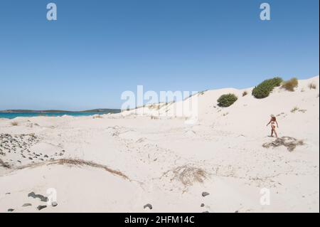 Young woman walking on a white sand beach in Porto Pino beach, Sardinia Stock Photo