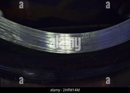 Steel part after turning lathe machining. Close-up of scratches, black painting ingot on background. Stock Photo