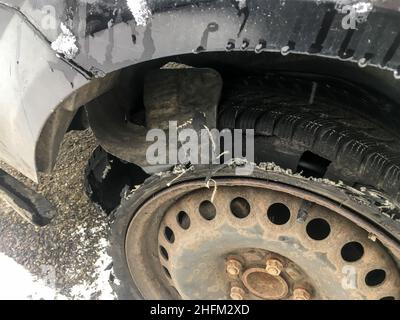 The detail of rusty wheel with flat, destroyed tire on the abandoned vehicle. The tire is completely broken with tread separated. Stock Photo