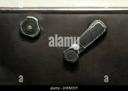 The detail of the black artificial leather  interior of the old classic car which needs a renovation. With ripped seat covers and rusty chrome parts. Stock Photo